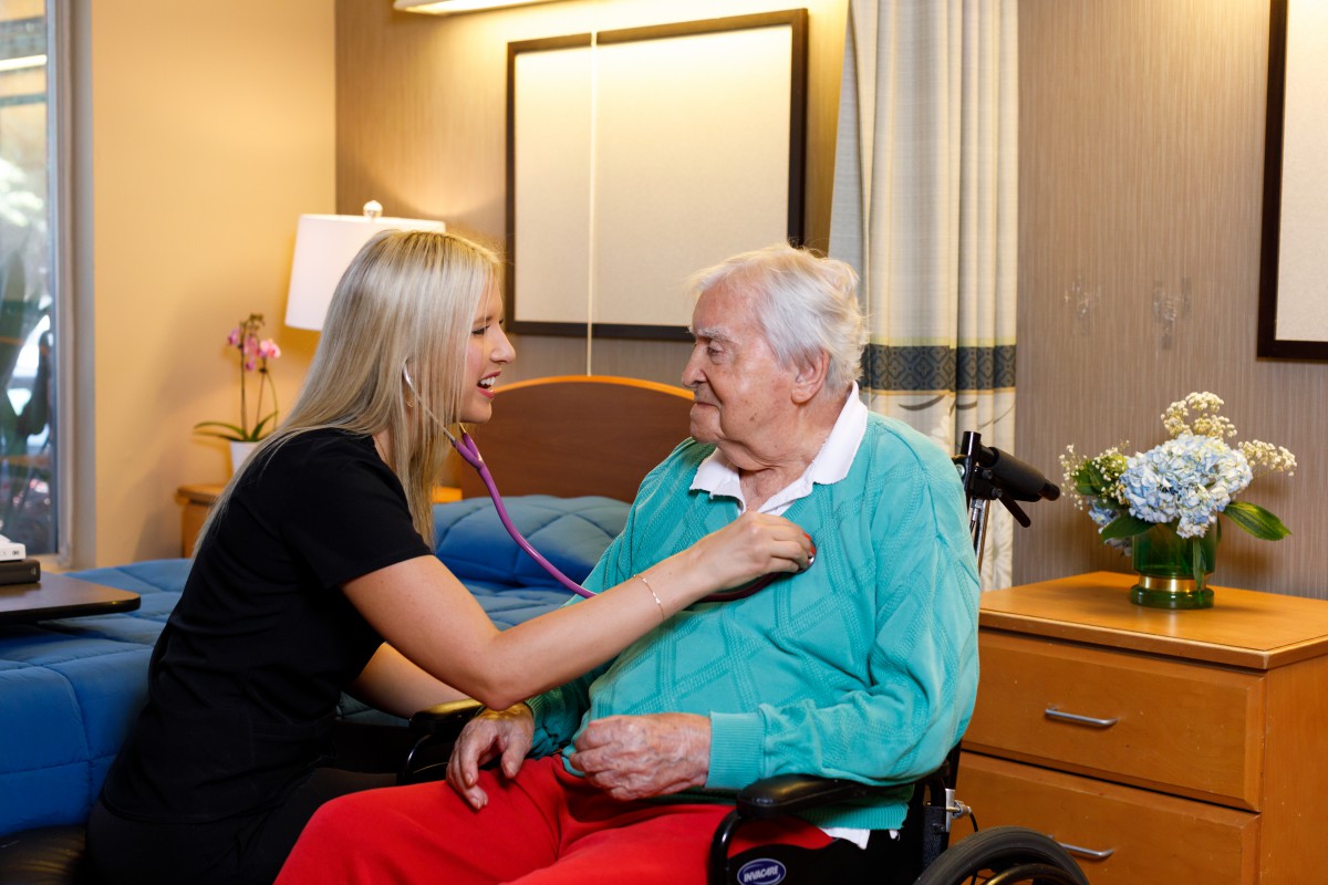 A nurse performs a health check-up on an elderly patient in a care facility.
