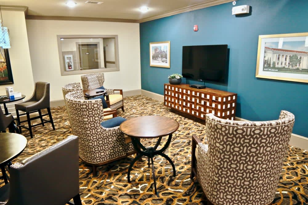 A cozy and elegantly decorated living room with patterned chairs, a television, and a stylish carpet.