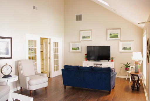 A cozy living room featuring a stylish blue sofa, a white armchair, and elegant wall art.
