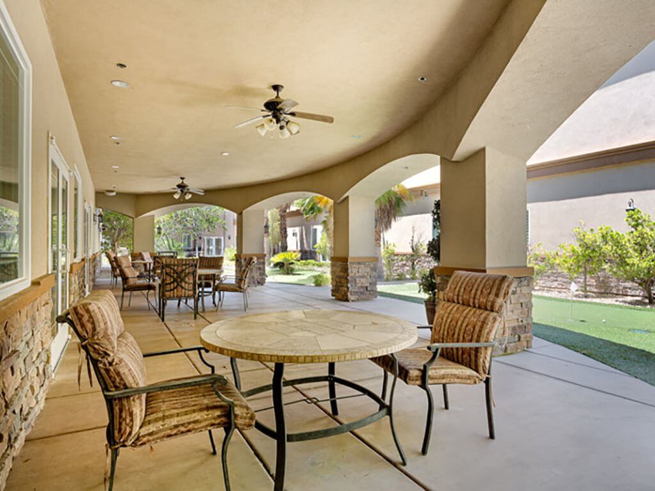 A spacious covered patio with a dining area overlooking a garden.