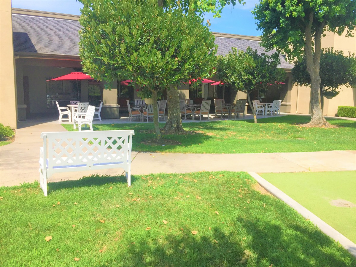 A peaceful outdoor garden area with benches and patio tables under red umbrellas.