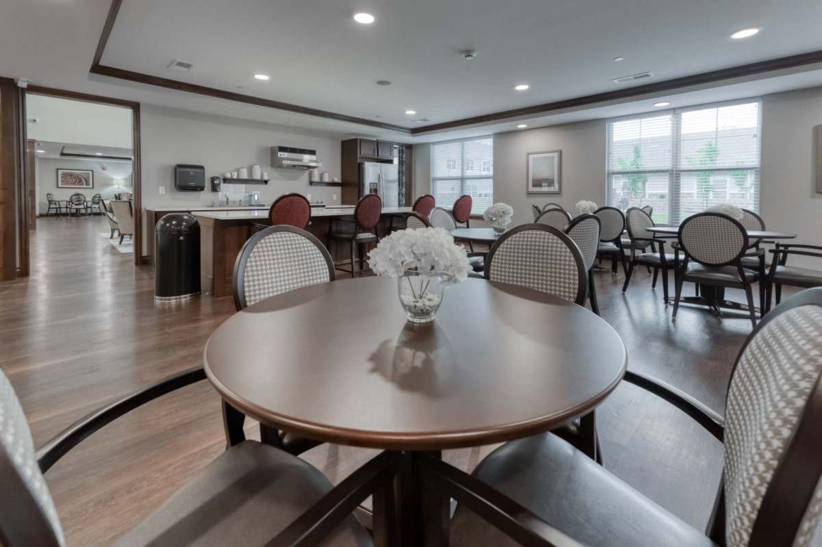 A modern dining area with neatly arranged tables and chairs, featuring a decorative vase in the center.