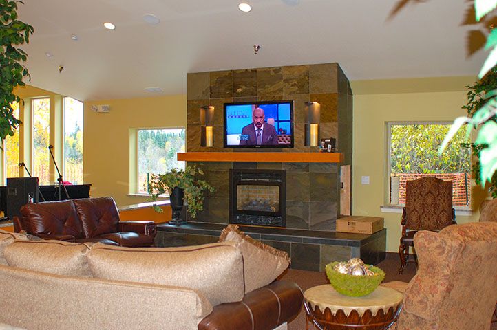 A cozy living room with a central fireplace and television, surrounded by comfortable seating.