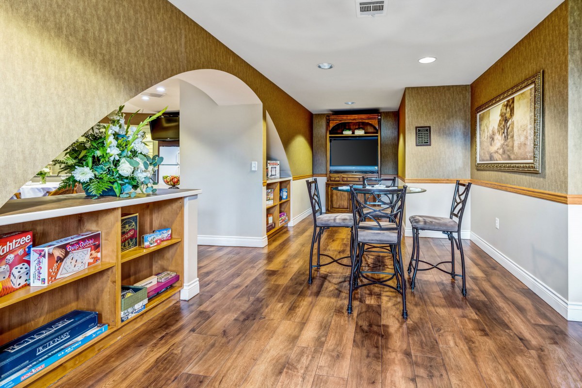 A cozy dining area with wooden flooring and arched openings leading to the kitchen.