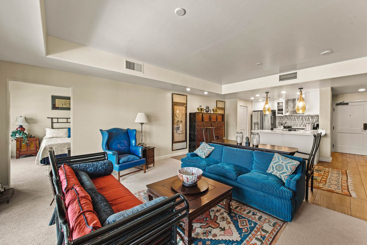 A modern living room featuring vibrant blue sofas and an open kitchen layout.