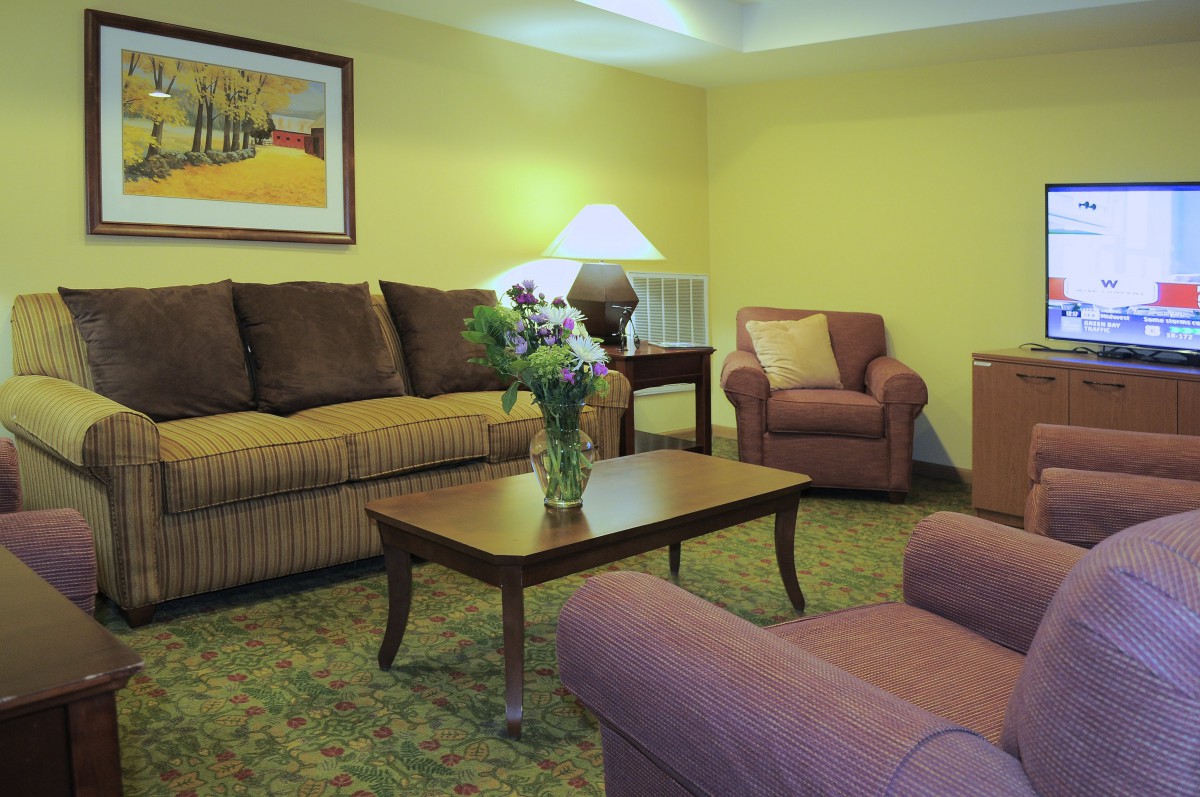 A cozy living room with a sofa, armchairs, and a coffee table topped with flowers under warm lighting.