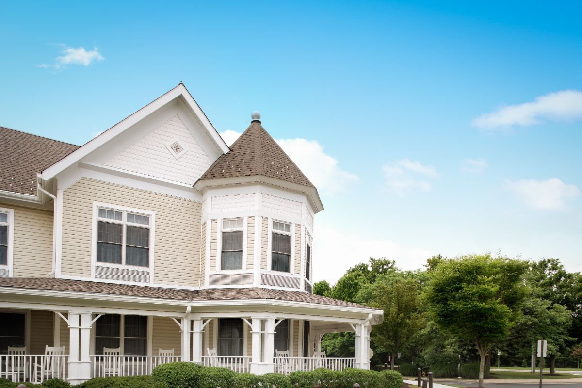 A charming Victorian-style house with a front porch against a blue sky.