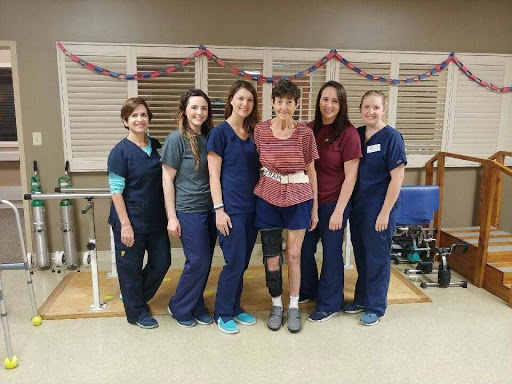 A dedicated team of healthcare professionals posing with a patient during rehabilitation.