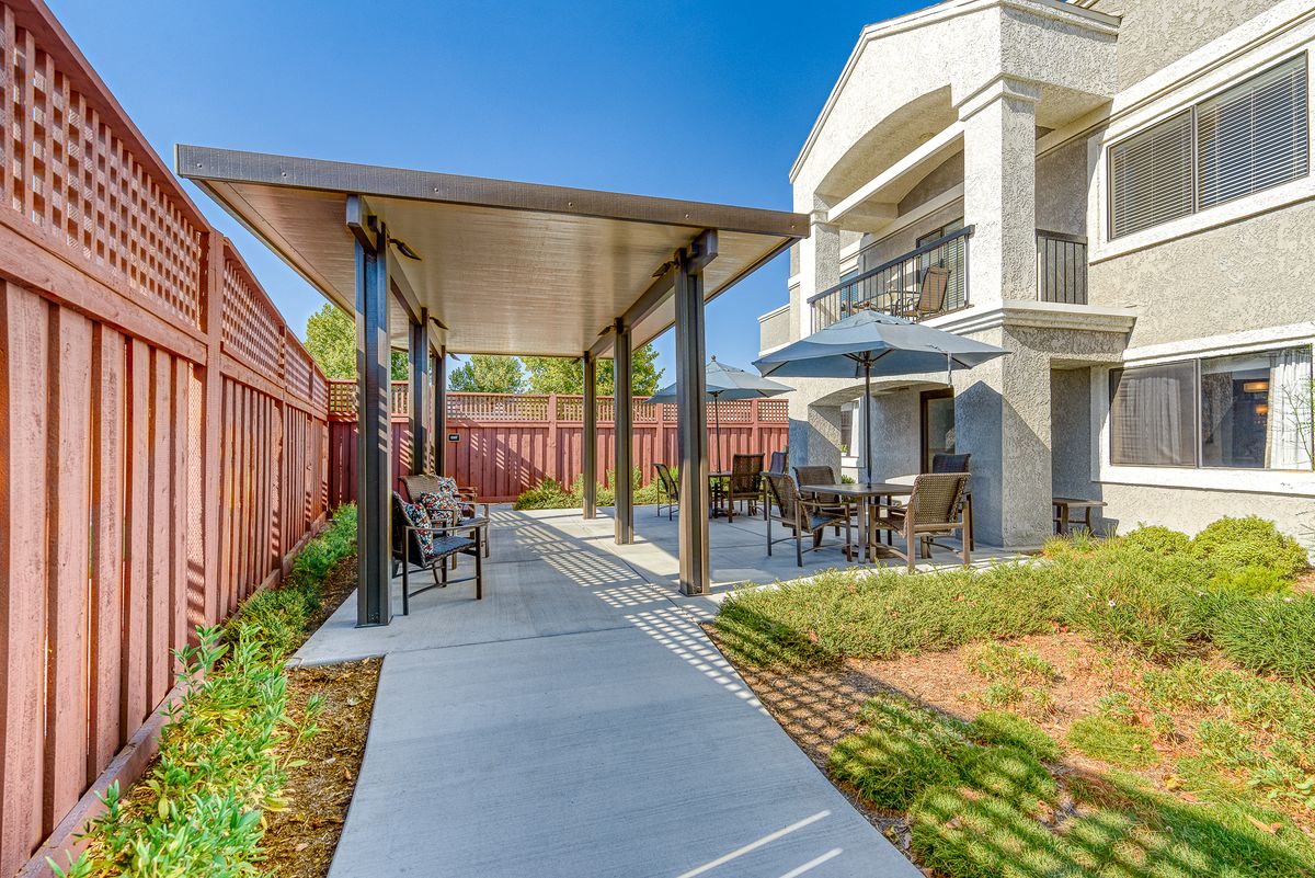 A well-maintained outdoor patio with seating areas and a pergola in a residential setting.