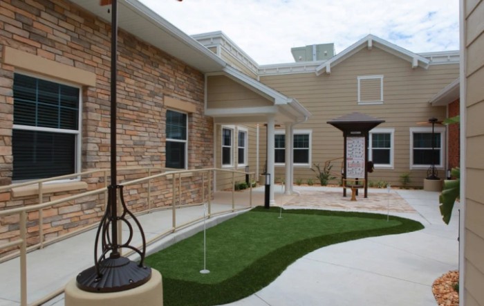 A modern building with a brick exterior, featuring a pathway and ramp leading to the entrance.