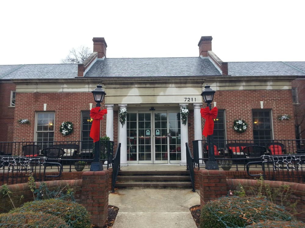 A festive brick building decorated with wreaths and red ribbons, featuring outdoor seating.
