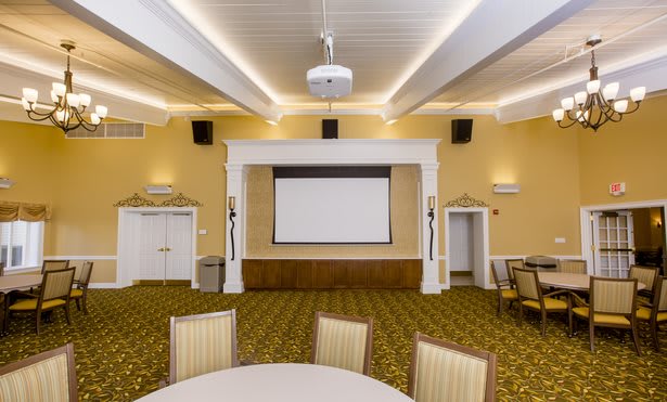 A well-lit conference room with a large projection screen and seating arrangement.