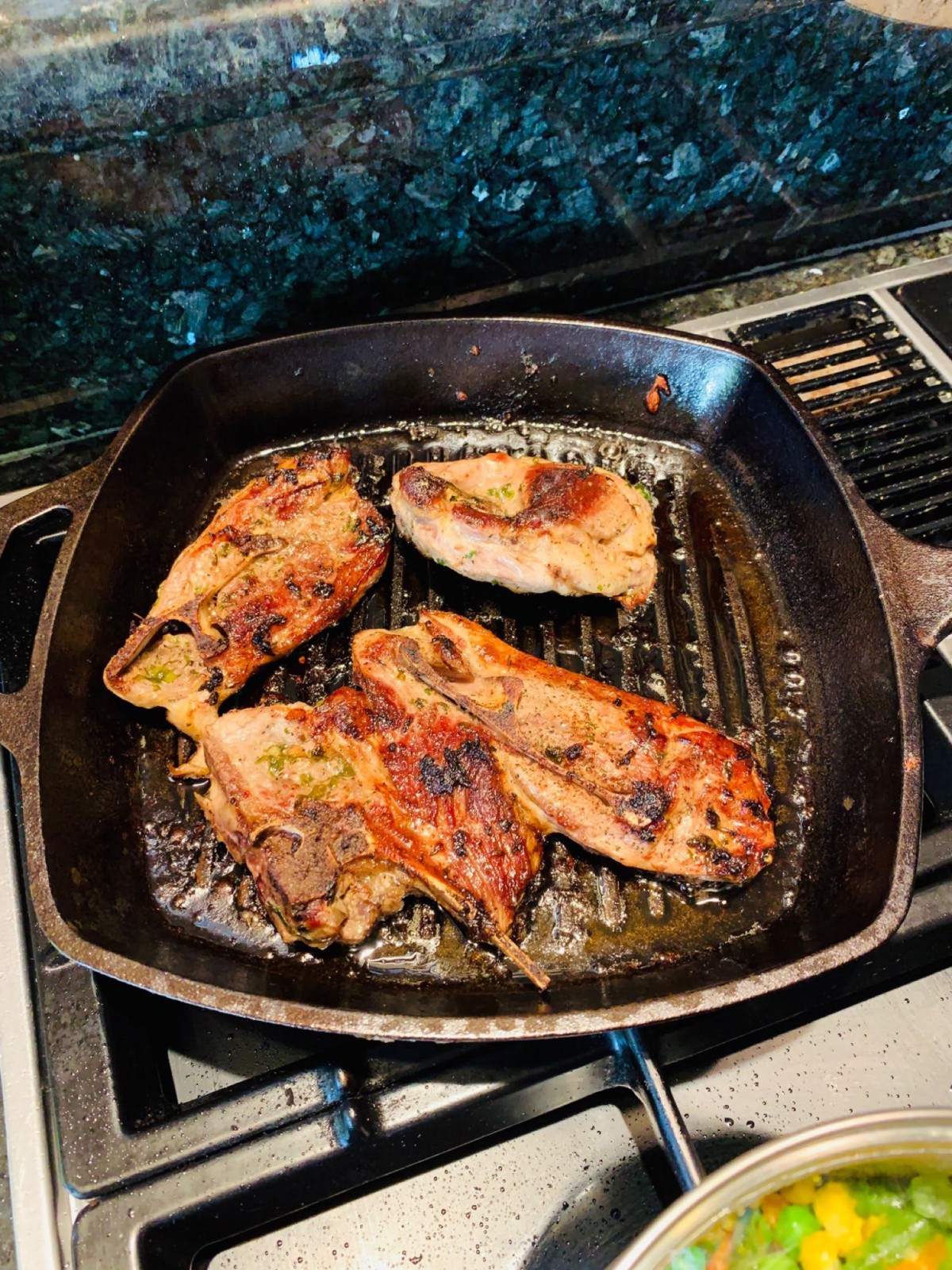 Grilled chicken breasts cooking in a cast iron skillet.