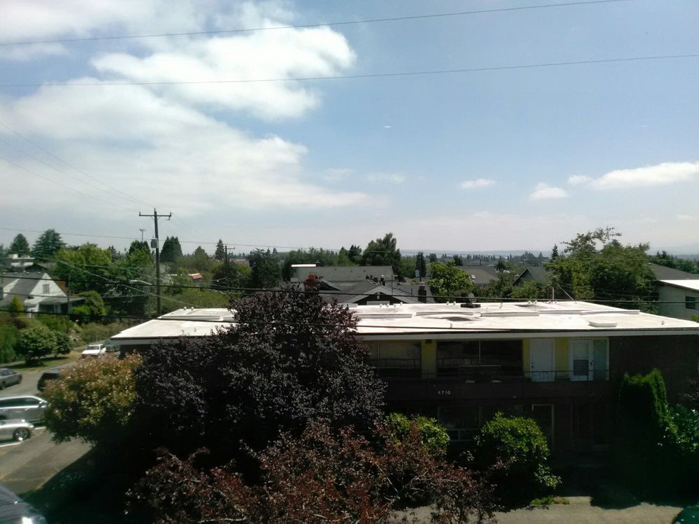 A suburban view with houses, trees, and a cloudy sky.