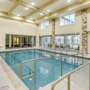 A spacious indoor swimming pool with large windows and bright lighting.