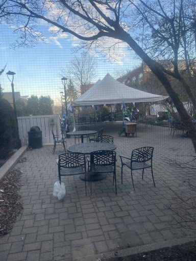 A serene outdoor setting featuring a tent, tables, and chairs under a clear sky.
