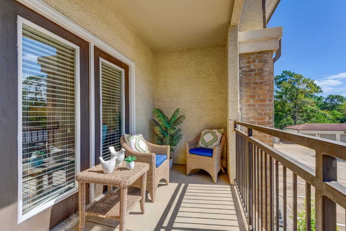 A cozy apartment balcony with comfortable seating and decorative elements.