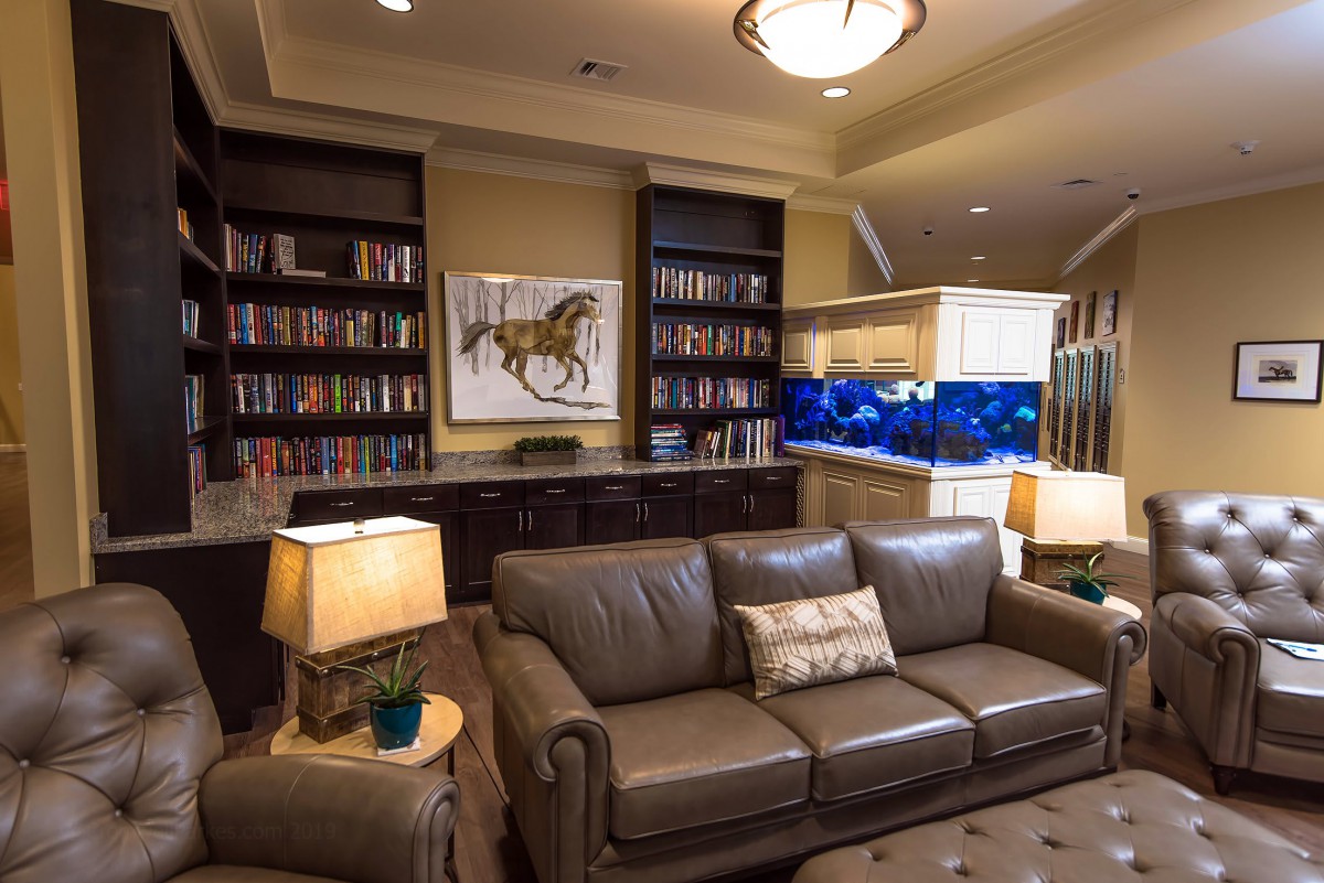 A cozy living room with bookshelves, a large sofa, and a vibrant aquarium.