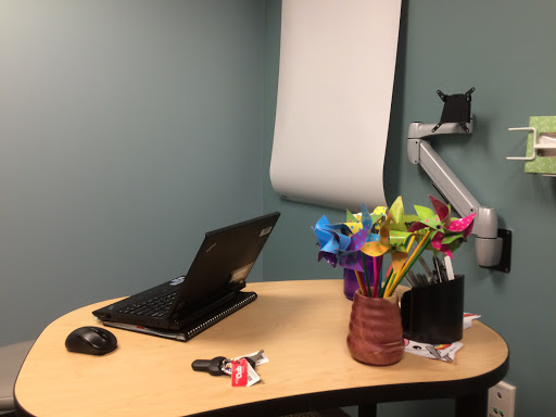 A cozy office workspace featuring a laptop, colorful pinwheels, and a neatly organized desk.