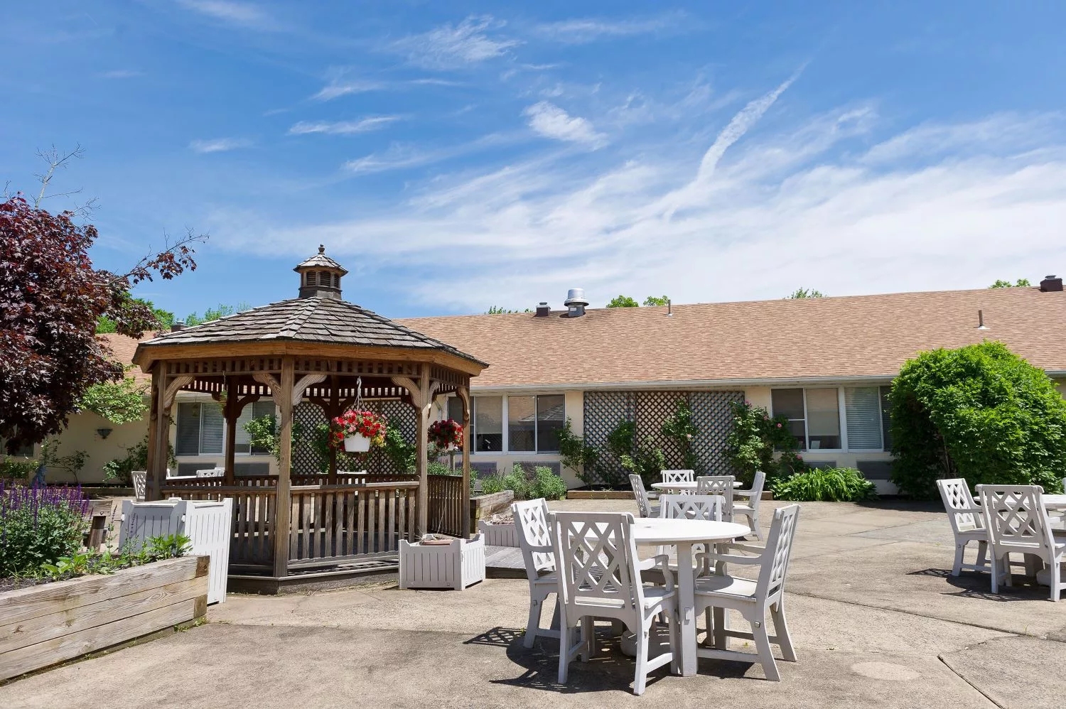 A spacious outdoor area featuring a wooden gazebo and patio furniture under a clear blue sky.