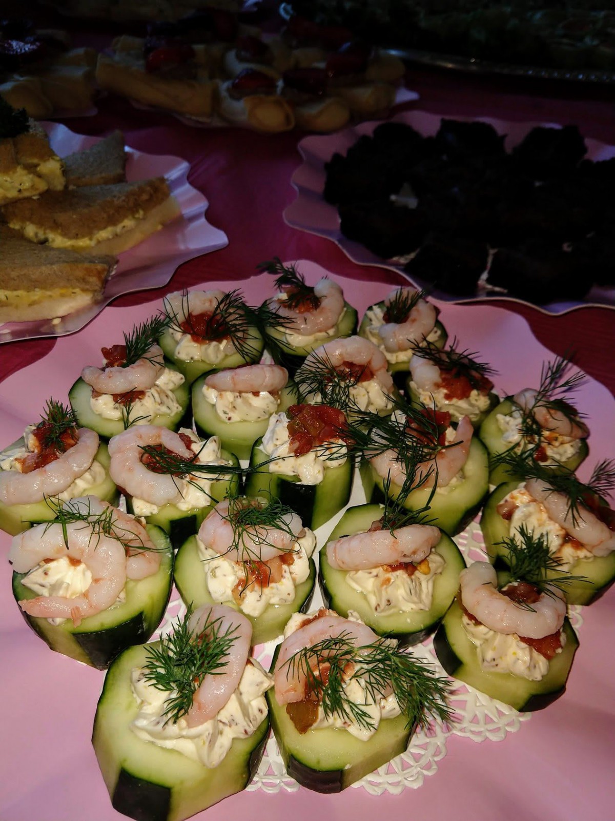 A platter of cucumber cups filled with shrimp and garnished with herbs.