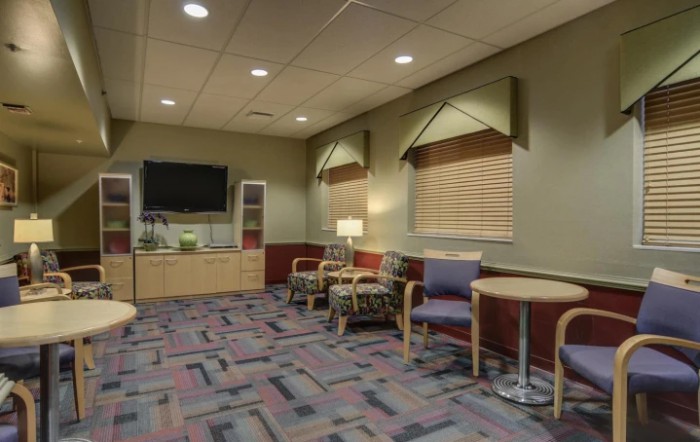 A cozy waiting room with comfortable seating, a television, and warm lighting.