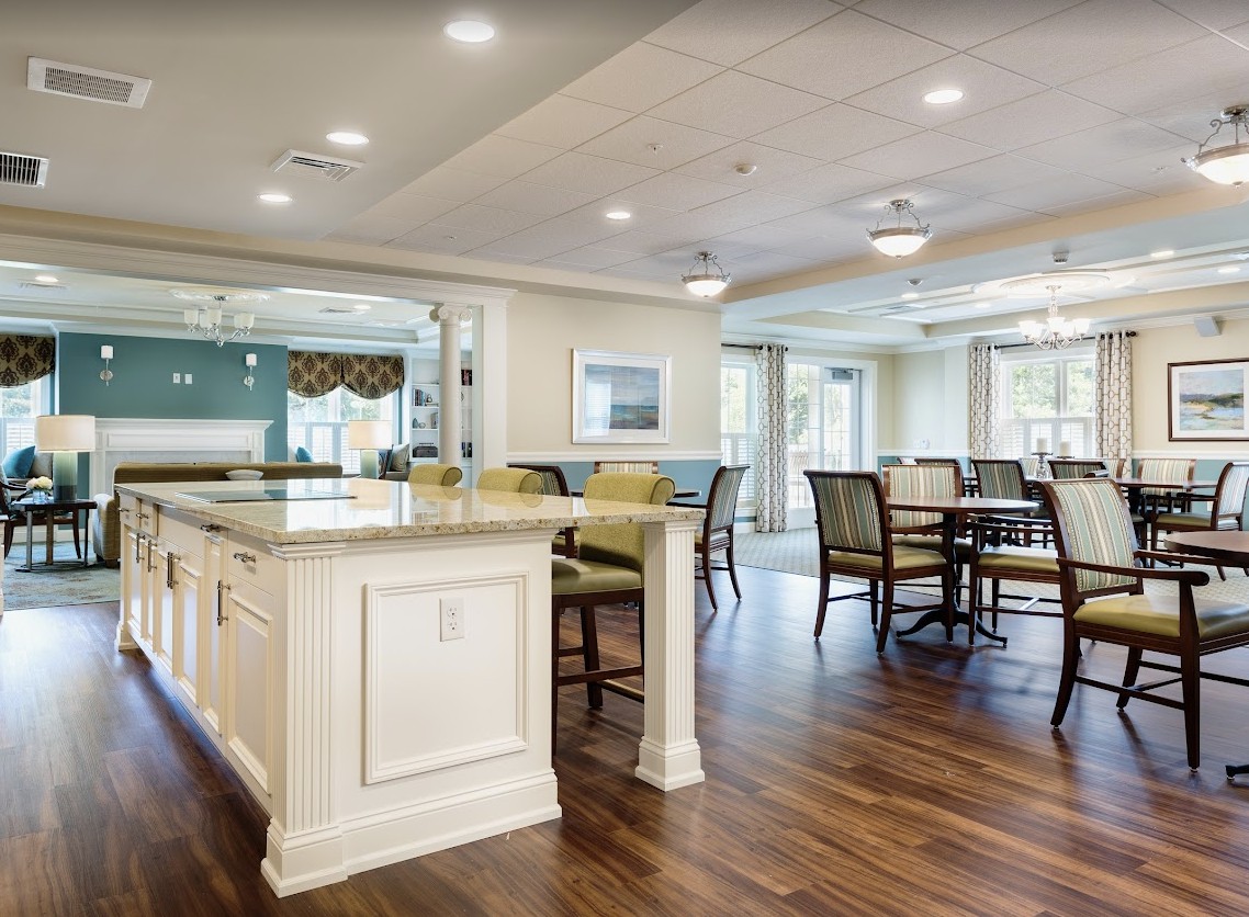 A spacious and modern kitchen with a dining area, featuring wood flooring and bright lighting.