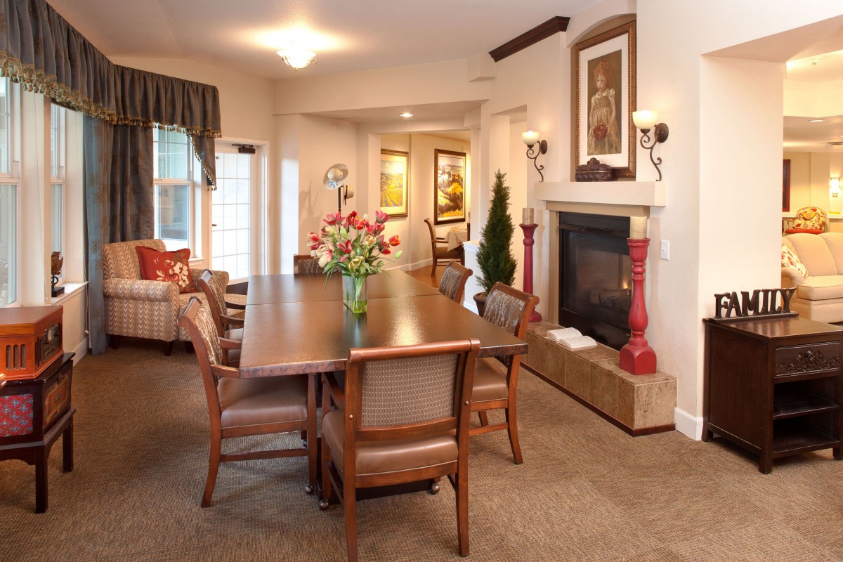 A cozy living and dining area featuring a wooden table, chairs, and a fireplace adorned with decorative elements.