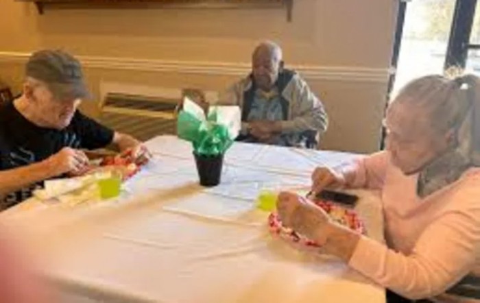 Elderly individuals gathered around a table in a social setting.