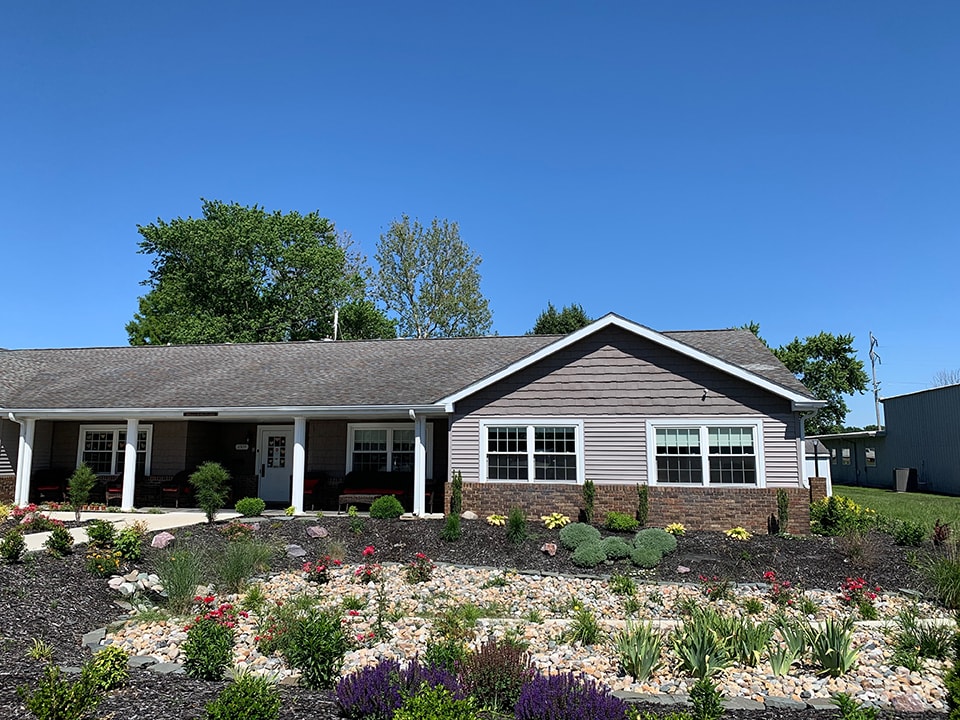 A single-story ranch-style house with a landscaped garden and clear blue sky.