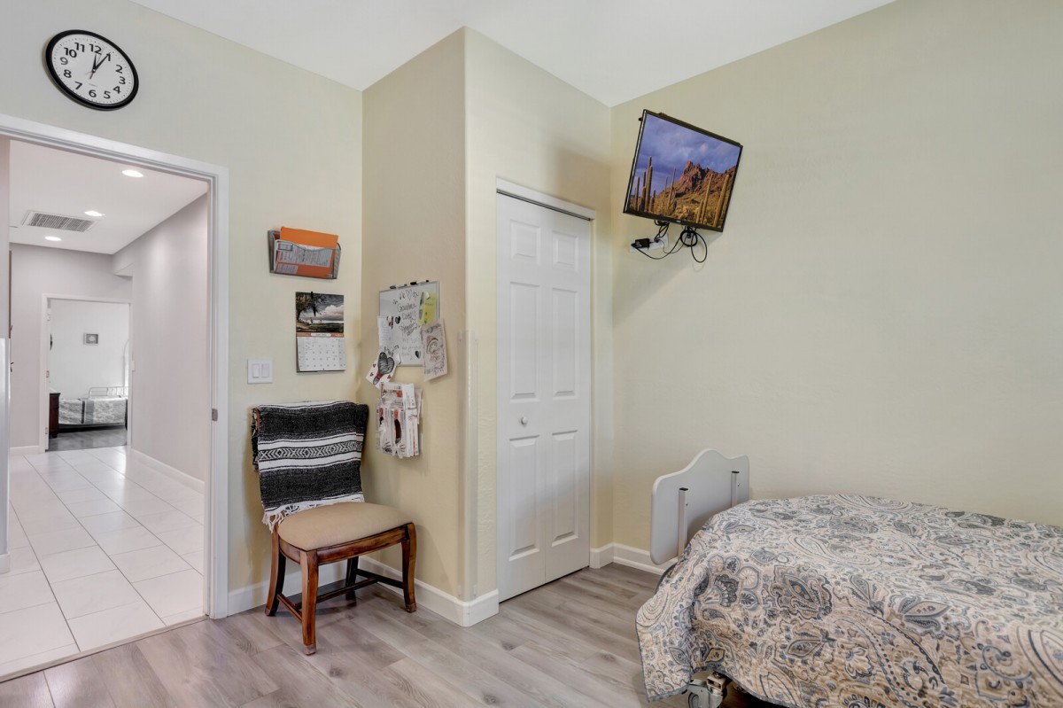 A cozy bedroom featuring a wall-mounted television, a chair, and a closet with sliding doors.