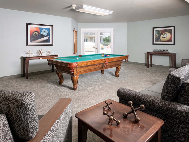 A well-furnished game room featuring a pool table, artwork, and comfortable seating.