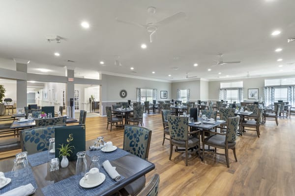 A spacious and well-lit dining room with neatly arranged tables and chairs.