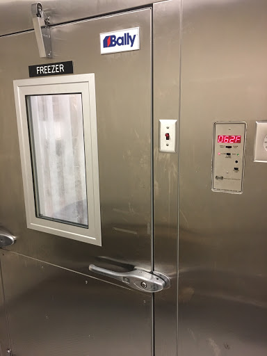 A metallic elevator door featuring a control panel and a small window labeled 'SHELTER'.