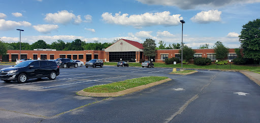 A spacious parking lot in front of a commercial building under a partly cloudy sky.