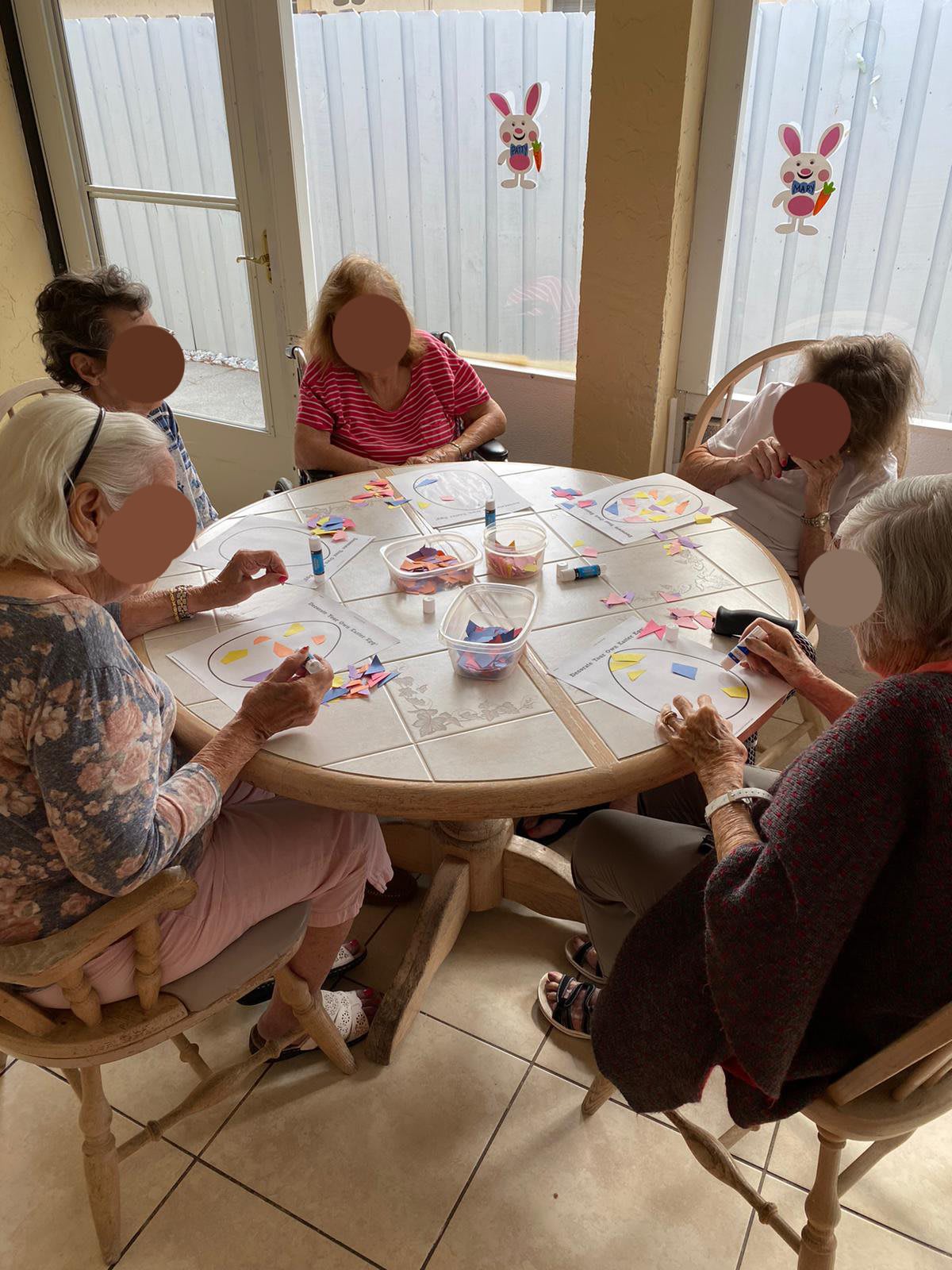 A group of seniors enjoying a painting activity around a table indoors.