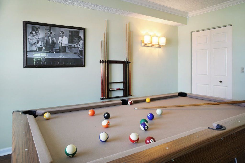 A cozy game room featuring a neatly arranged pool table with cue sticks on the wall.