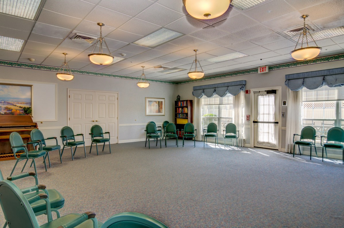 An empty meeting room with chairs arranged in a circle, carpeted floor, and large windows.