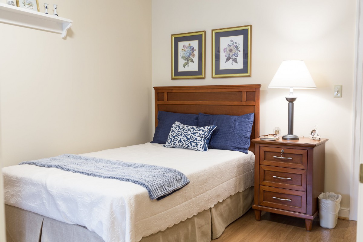 A cozy bedroom with a neatly made bed, nightstand, and decorative wall art.
