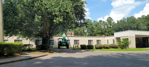 Workers using a lift to work on the roof of a building, surrounded by trees under a clear blue sky.