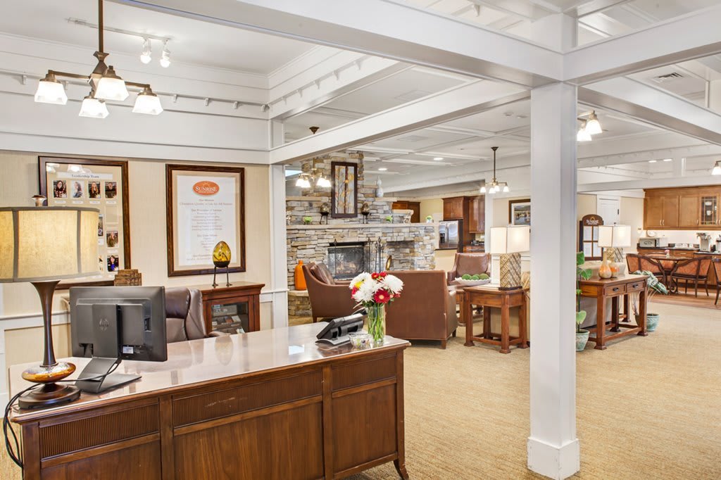 A cozy office lobby with a reception desk, comfortable seating, and decorative elements.
