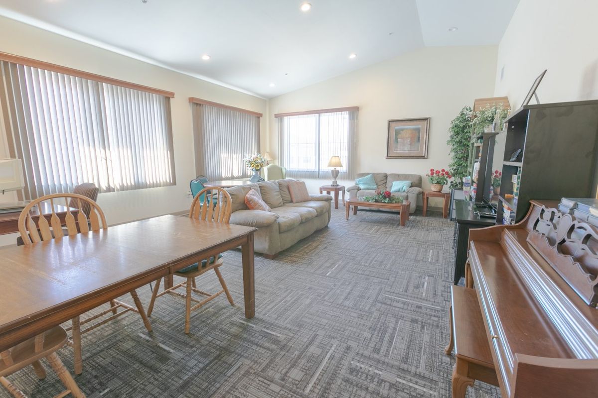 A spacious living room with comfortable seating, a large table, and ample natural light from the windows.