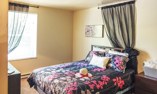 A cozy bedroom with floral bedding and sheer curtains.