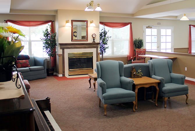 A cozy living room with armchairs, a sofa, and a fireplace.