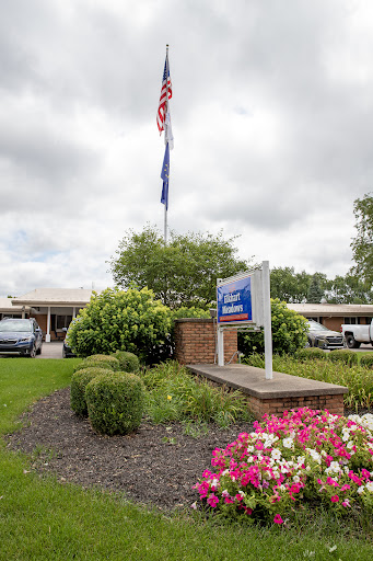 A welcoming view of a facility with an American flag and colorful flowers in the foreground.
