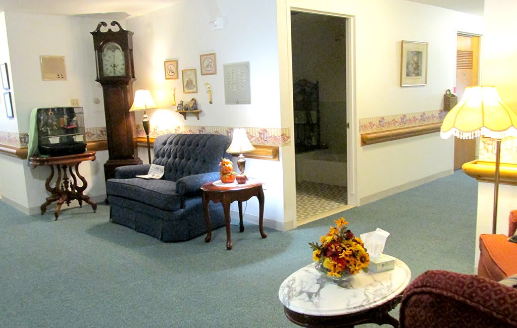 A cozy living room with a sofa, table lamps, and a grandfather clock.