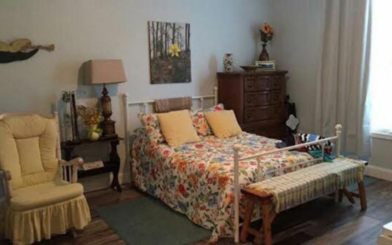 A cozy vintage-style bedroom with a floral bedspread and classic furniture.