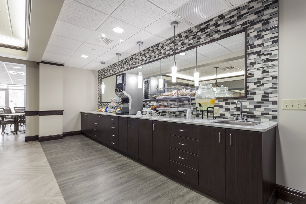 A modern kitchen interior featuring sleek cabinetry, a large mirror, and contemporary lighting fixtures.