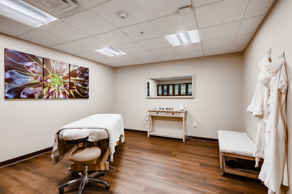 A serene massage room equipped with a treatment bed and soothing decor.