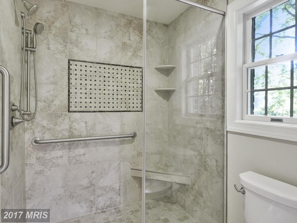 A modern bathroom with a glass-enclosed shower and tiled walls.